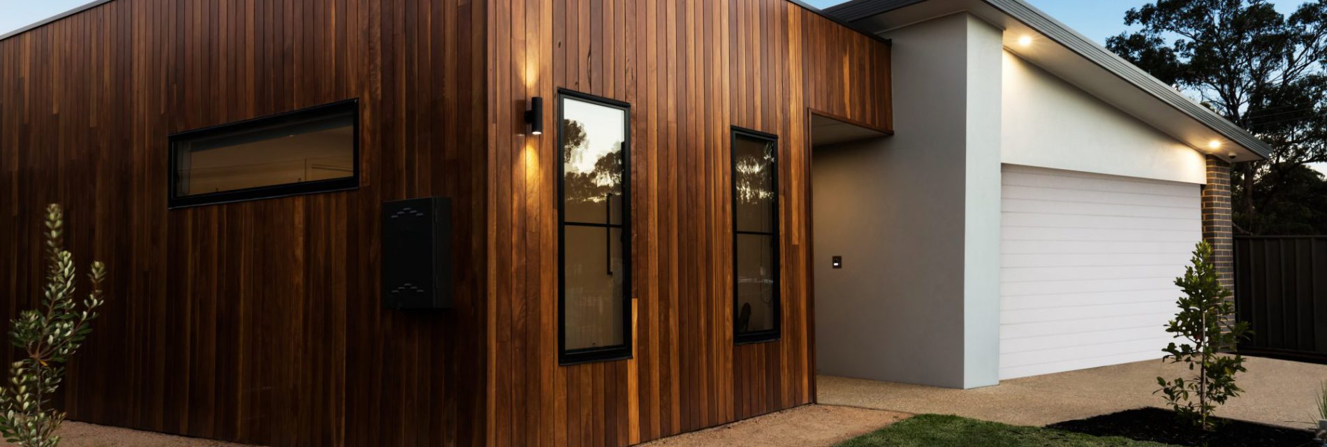 Extension de maison en murs ossature bois avec toit plat et garage en murs béton avec crépi enduit et toit charpente traditionnelle